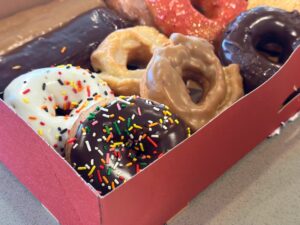 a box of Top Pot doughnuts in Seattle, featuring a chocolate sprinkle donut in the corner